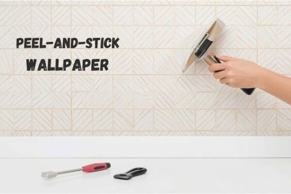 Person applying peel-and-stick wallpaper on a smooth kitchen wall with a squeegee, with a cutter, level, and cloth nearby in a clean modern kitchen.