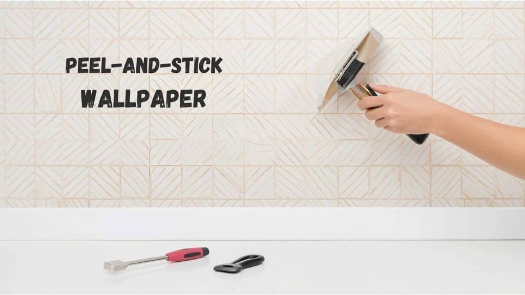 Person applying peel-and-stick wallpaper on a smooth kitchen wall with a squeegee, with a cutter, level, and cloth nearby in a clean modern kitchen.
